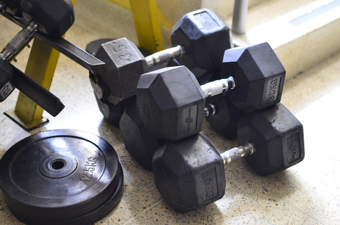 Hexagonal weight dumbbells and 2.5 kg weight plates on gym floor for fitness culture supplements workout enhancement