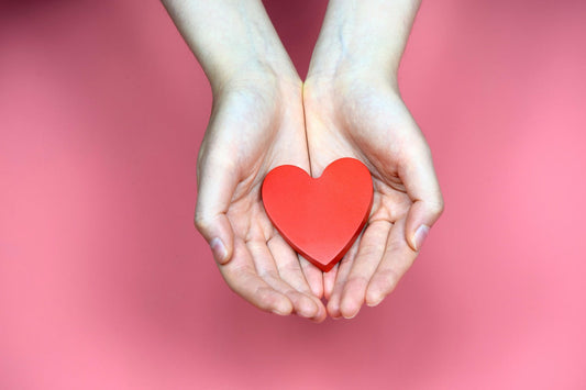 Hands holding a red heart shape symbolizing how to improve heart health fast with L-Arginine and CoQ10 supplements.
