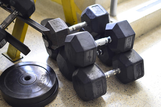 Hexagonal weight dumbbells and 2.5 kg weight plates on gym floor for fitness culture supplements workout enhancement