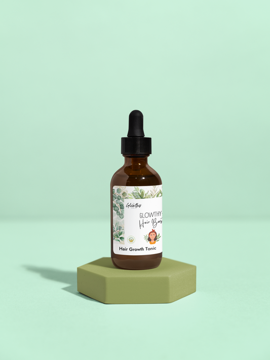 Amber glass bottle of GLOWTHY+ Hair Growth Tonic with black dropper, 2oz, placed on a green hexagonal stand.